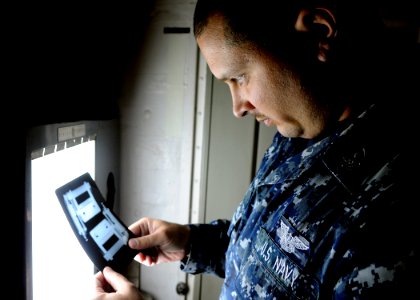 US Navy 101028-N-1004S-041 Aviation Structural Mechanic 2nd Class Kenneth Perez, from Turlock, Calif., inspects an x-ray of equipment aboard the ai photo