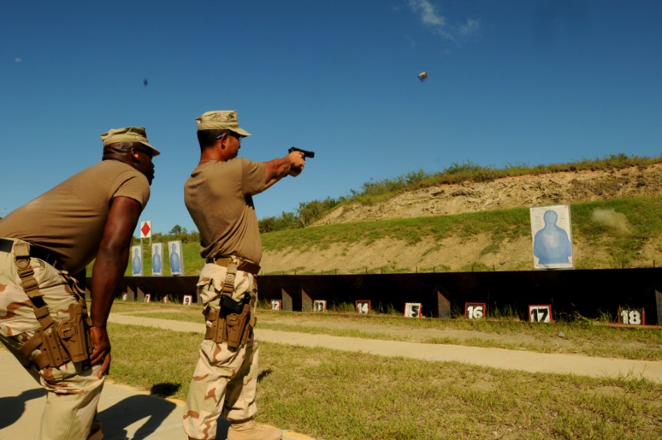US Navy 101028-N-4936C-240 Aviation Warfare Systems Operator Chief Eddie Gomez fires a 9 mm pistol as firing line coach Master-at-Arms 1st Class Er