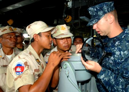 US Navy 101026-N-9156C-003 Quartermaster 2nd Class John Ostgard explains navigation equipment on the bridge of the guided-missile frigate USS Cromm