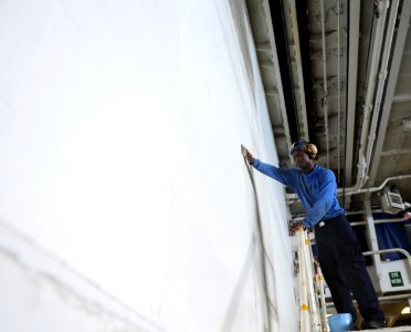 US Navy 101101-N-3793B-046 Aviation Boatswain's Mate (Handling) Airman Raysean Sharpe, from San Diego, scrubs the bulkhead in the hangar bay of the