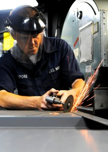 US Navy 101102-N-1004S-065 Machinery Repairman Fireman Mark Lepore, from Rochester, N.Y., uses a pneumatic die grinder to cut wiring holes in the b photo