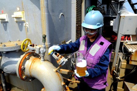 US Navy 101027-N-8335D-045 Engineman 3rd Class Courtney Arce tests fuel for impurities as it is pumped aboard the amphibious dock landing ship USS