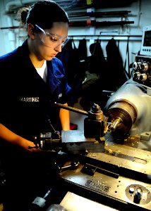 US Navy 101102-N-1004S-144 Machinery Repairman Fireman Gabriel Martinez, from Great Falls, Mont., uses a lathe machine to turn down a piece of roun