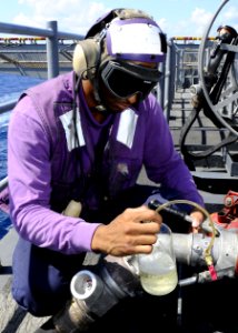 US Navy 101102-N-3154P-032 Aviation Boatswain's Mate (Fuels) 3rd Class Sean White takes fuel samples during an underway replenishment aboard the am