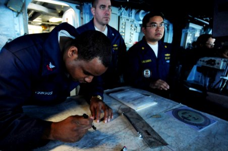 US Navy 101107-N-3659B-193 Quartermaster 2nd Class Darren Griggs, left, from Austin, Texas, plots a course on a navigation chart aboard the amphibi