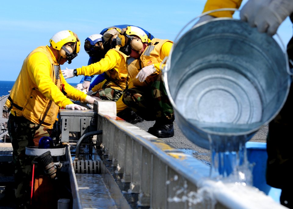 US Navy 101106-N-5538K-154 Aviation boatswain's mates clean wheel stop combing aboard the forward-deployed amphibious assault ship USS Essex (LHD 2