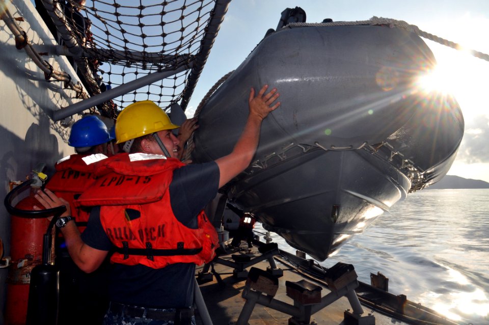 US Navy 101111-N-7293M-778 Boatswain's Mate Seaman Dustin Holroyd and members of the deck department guide a 7-meter rigid hull inflatable boa
