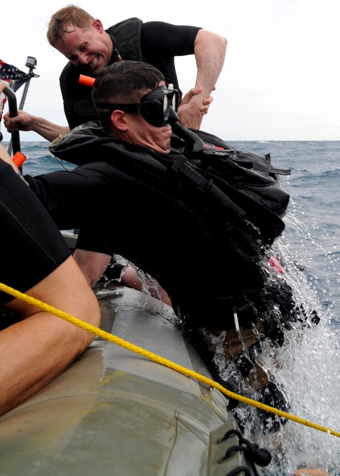 US Navy 101108-N-0120A-076 Boatswain's Mate 1st Class Kurt Bartholomai helps Aviation Warfare Systems Operator 2nd Class Ricky Crumley into a rigid
