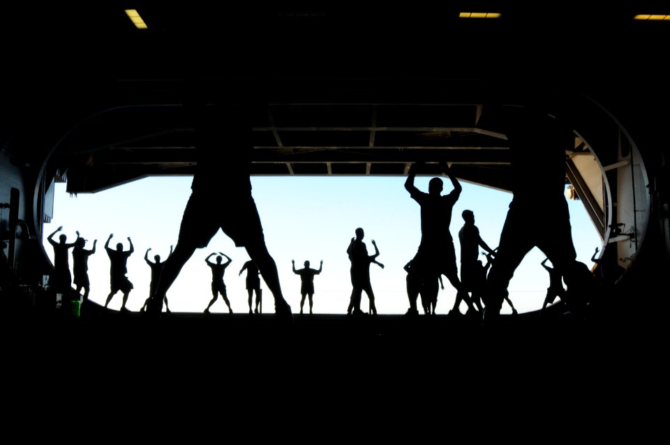 US Navy 101112-N-9132C-184 Sailors from the engineering repair division perform jumping jacks during group physical training in the hangar bay of t