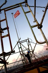 US Navy 101108-N-9643K-371 Hospital Corpsman 1st Class L. Chan prepares to lower the Navy Jack amidst the scaffolding on the flight deck of the amp