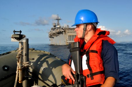 US Navy 101111-N-7293M-712 Seaman Ryan Owens stands a force protection watch in a 7-meter rigid hull inflatable boat while the amphibious transport