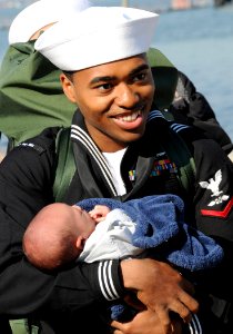 US Navy 101118-N-6125G-108 Aviation Boatswain's Mate (Handling) 3rd Class Bryant Johnston holds his new son at Naval Station Norfolk after a four