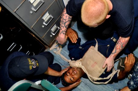 US Navy 101112-N-7293M-084 Seaman Cyle Cason holds Quartermaster 3rd Class Edir Coronado's head immobile as Culinary Specialist 2nd Class Eric Stro
