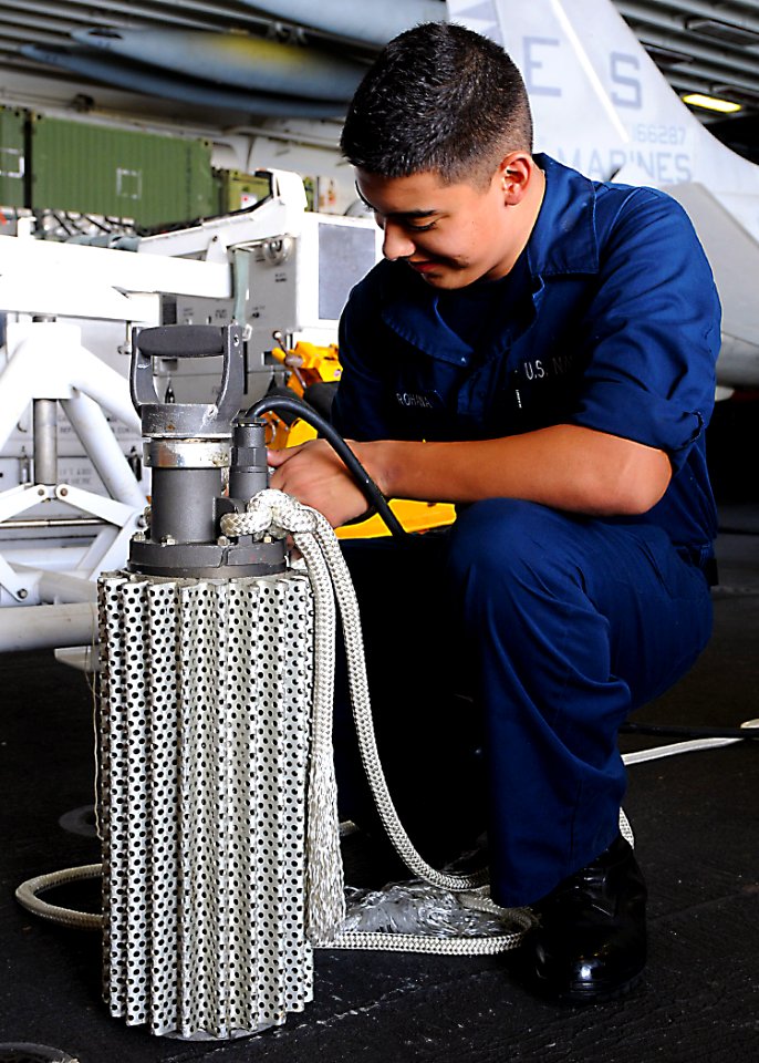 US Navy 101116-N-2908M-009 Damage Controlman Fireman Luis Baezarohana attaches a line to an electrical submersible pump to prepare for a damage con
