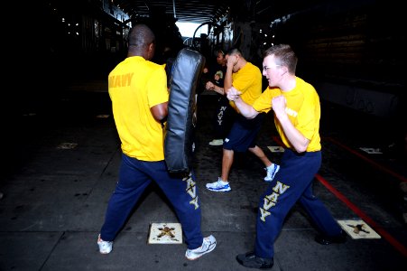 US Navy 101118-N-8335D-203 Operations Specialist Seaman Recruit Stephen Roycroft punches a bag held by Hospitalman Ndudic Chukwudozie during the me