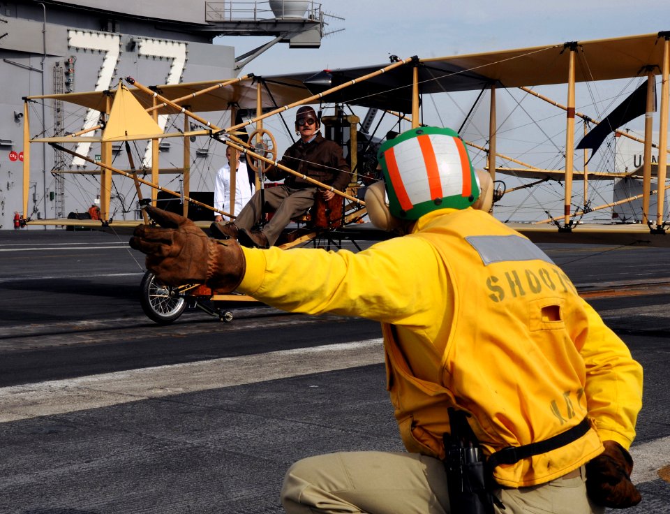 US Navy 101115-N-3885H-191 A shooter signals to retired Cmdr. Bob Coolbauth, the pilot of a replica of a Curtiss-Ely Pusher