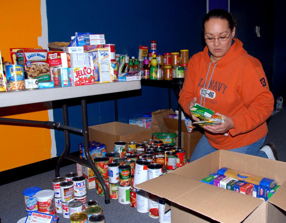 US Navy 101119-N-6764G-003 Information Systems Technician 1st Class Angelita Tester sorts through non-perishable food items for the non-profit Arme