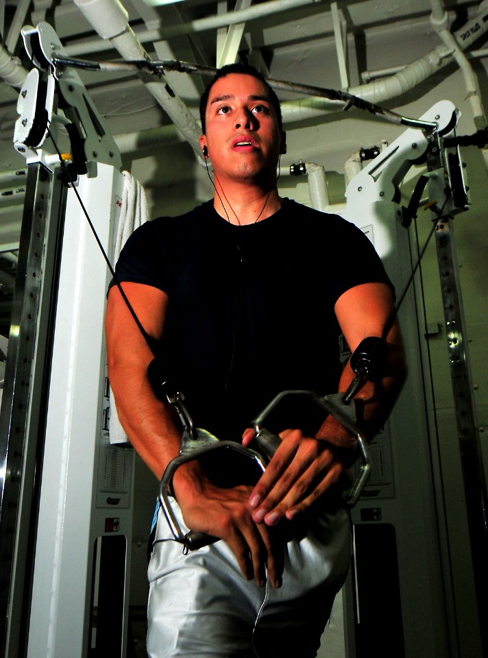 US Navy 101122-N-7948R-079 Yeoman 3rd Class Benjamin Castillo performs cable flyes in the gym aboard the amphibious dock landing ship USS Pearl Har