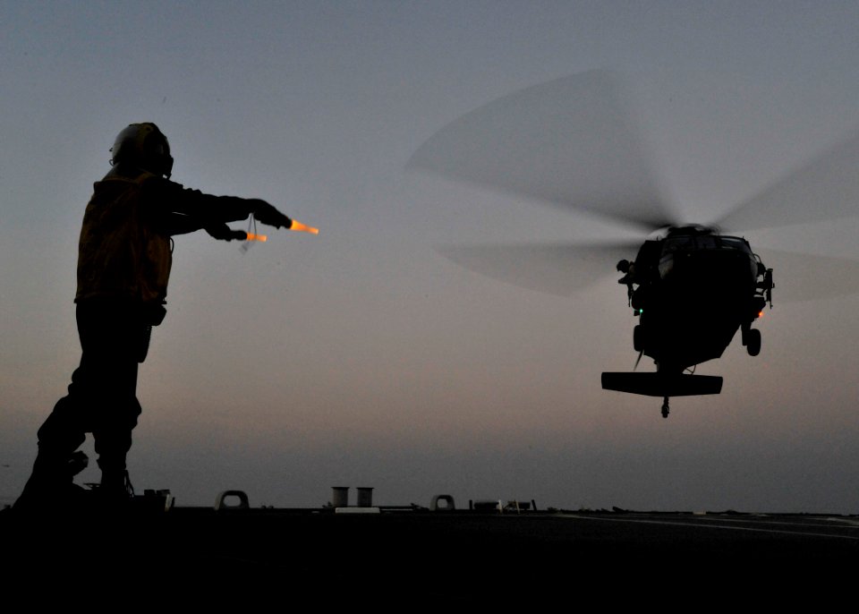 US Navy 101120-N-6499D-283 Boatswain's Mate Seaman Kossi Sewonu signals a U.S. Army UH-60S Black Hawk helicopter to land aboard the guided-missile