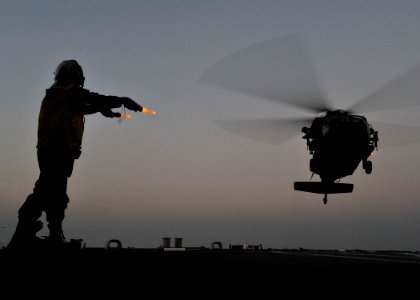 US Navy 101120-N-6499D-283 Boatswain's Mate Seaman Kossi Sewonu signals a U.S. Army UH-60S Black Hawk helicopter to land aboard the guided-missile