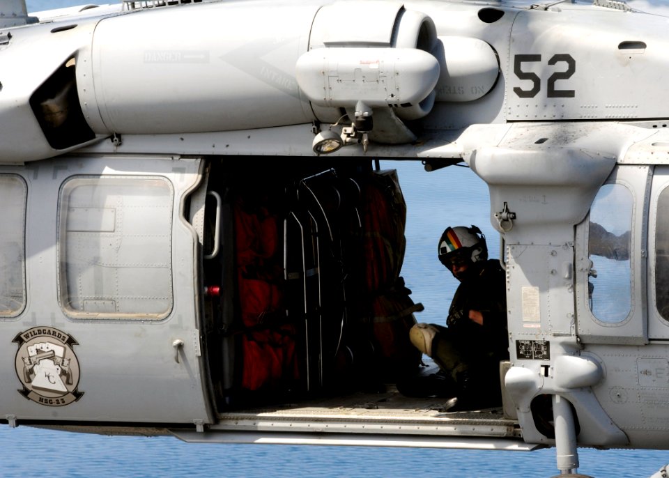 US Navy 101119-N-3729D-074 An aviation warfare search and rescue swimmer rides in an MH-60S Sea Hawk helicopter, assigned to the Wild Cards