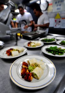 US Navy 101128-N-7948R-344 Sailors and Marines work on a main course in the galley during an Iron Chef competition aboard the amphibious dock landi