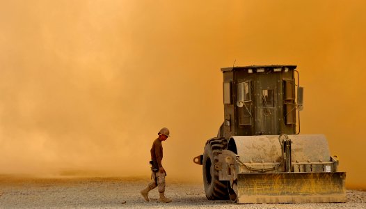 US Navy 101123-N-6436W-010 A Seabee assigned to Naval Mobile Construction Battalion (NMCB) 40 walks to his equipment in a cloud of dust created by