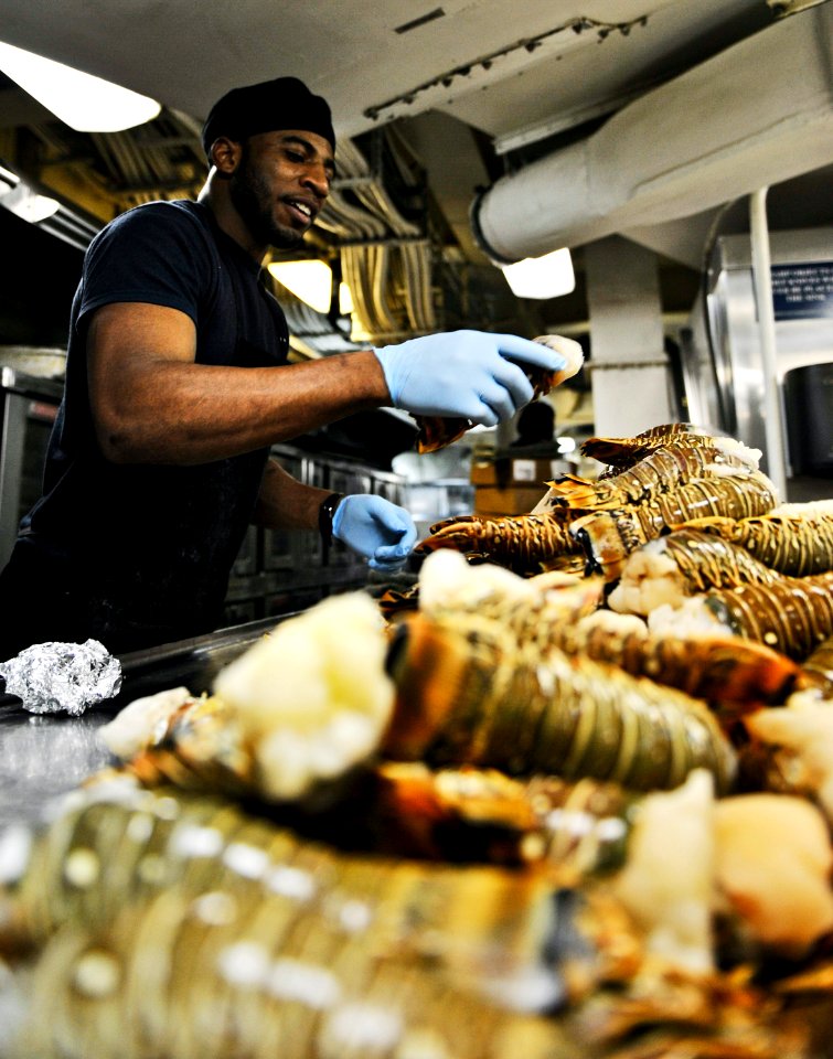 US Navy 101125-N-6003P-009 Culinary Specialist Seaman Derrick Roach, from Jackson, Miss., prepares lobster tails for Thanksgiving dinner in the gal