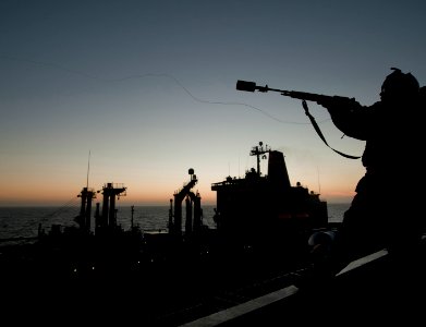 US Navy 101201-N-7981E-111 Gunner's Mate 2nd Class John Brown fires a shot line to the Military Sealift Command fleet replenishment oiler USNS Yuko