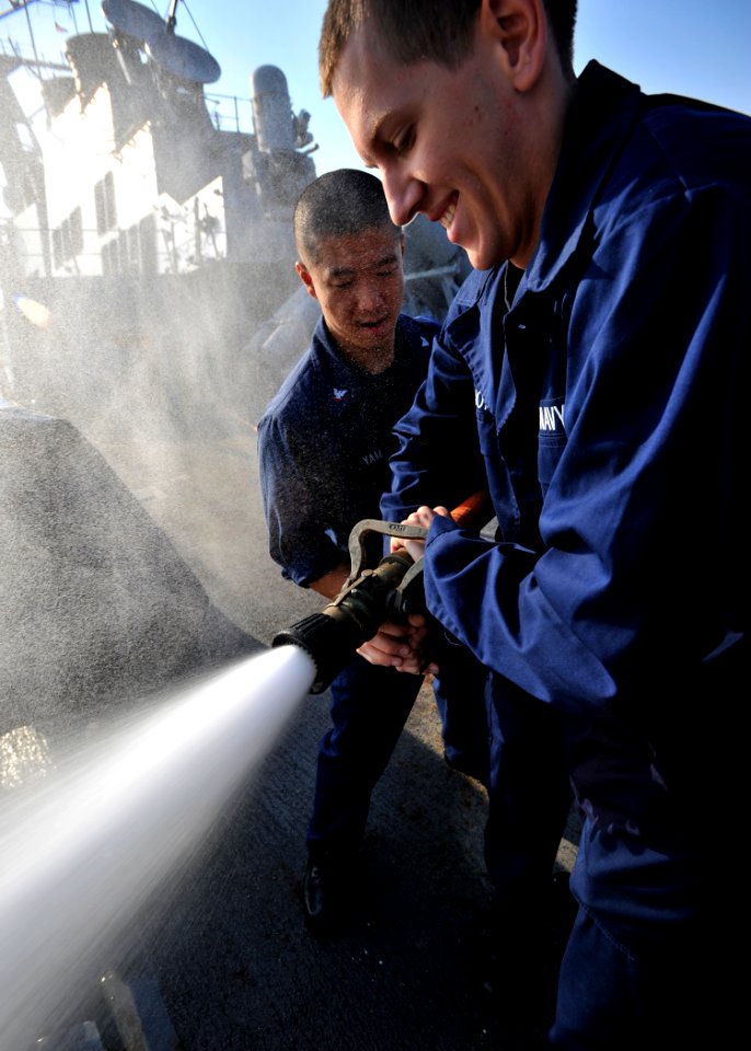 US Navy 101122-N-6499D-034 Damage Controlman 3rd Class Ricky Yam, left, demonstrates proper firefighting techniques to Quartermaster Seaman Recruit