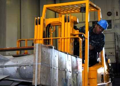 US Navy 101201-N-4590G-090 Aviation Ordnanceman Airman Corey Harfield, from Memphis, Tenn., maneuvers a forklift carrying ordnance through the hang