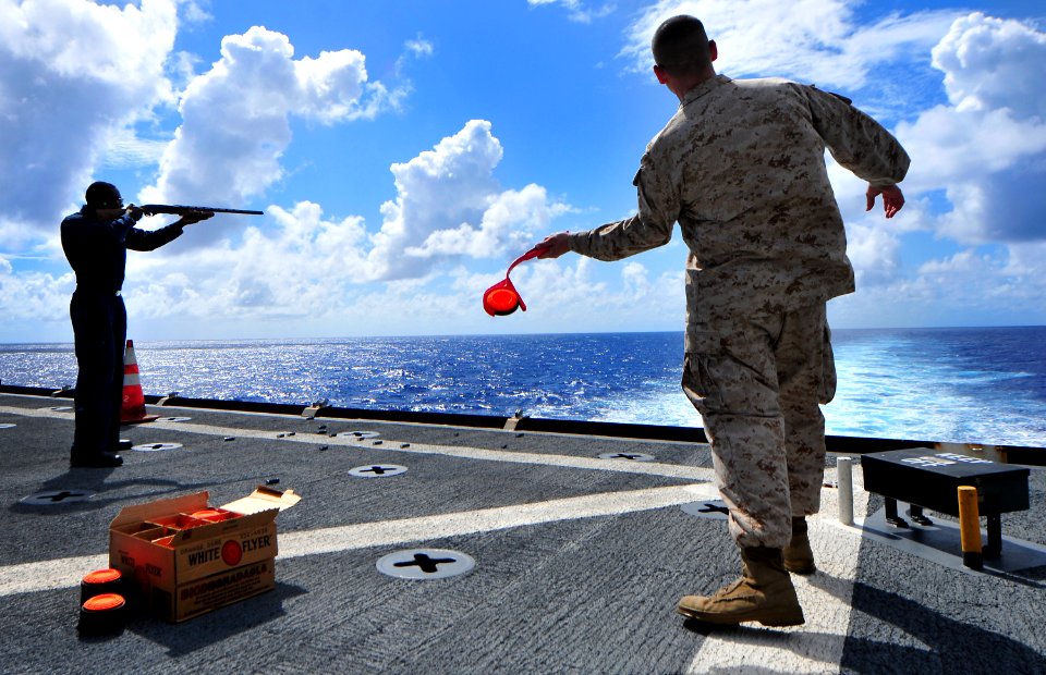 US Navy 101128-N-7948R-132 Boatswain's Mate Seaman Alonzo Bender, left, fires a 12-gauge shotgun during a morale, welfare and recreation skeet shoo