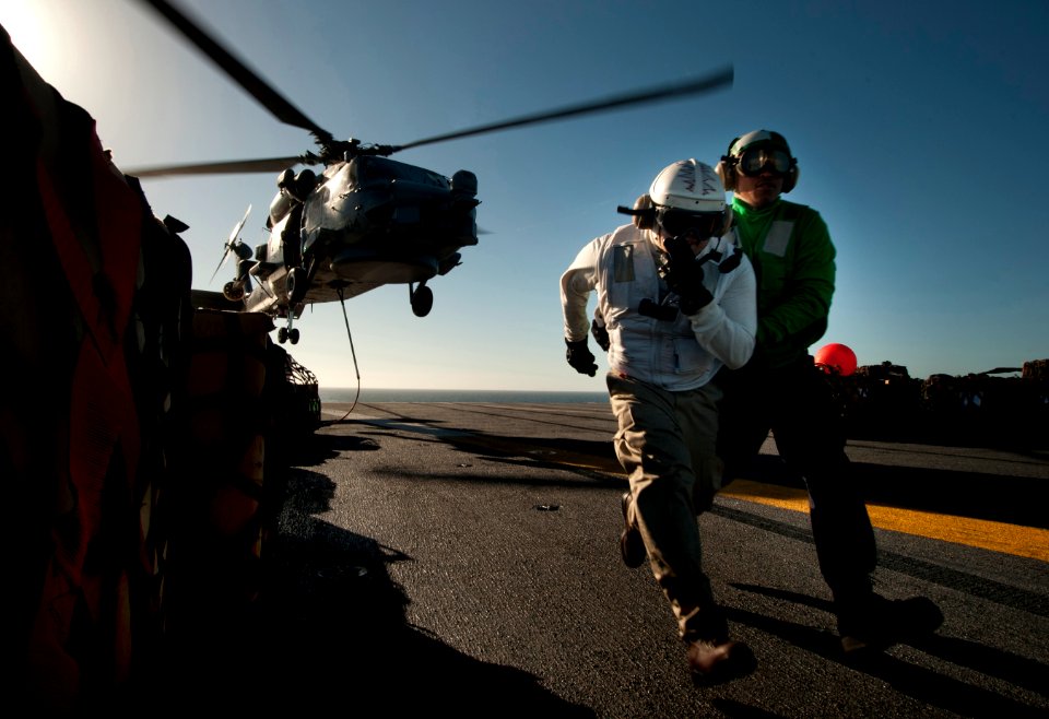 US Navy 101201-N-7981E-808 Lt. j.g. Dennis Pelina and Ship's Serviceman 3rd Class Tyriek Lyons run to clear the danger area after attaching cargo t