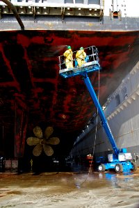 US Navy 101202-N-9643K-012 NASSCO shipyard workers use high-pressure water to clean the hull of the amphibious assault ship USS Bonhomme Richard (L