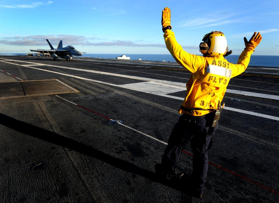 US Navy 101204-N-2055M-312 An aircraft director signals to a pilot after a safe landing aboard the aircraft carrier USS Carl Vinson (CVN 70)