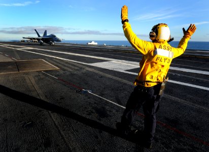 US Navy 101204-N-2055M-312 An aircraft director signals to a pilot after a safe landing aboard the aircraft carrier USS Carl Vinson (CVN 70)