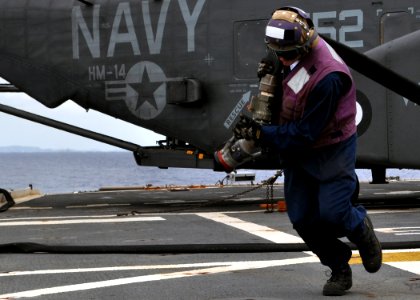 US Navy 101205-N-3620B-048 Aviation Boatswain's Mate (Fuel) Airman Richard Bove moves a JP-5 hose behind the foul line after hot-refueling an MH-53