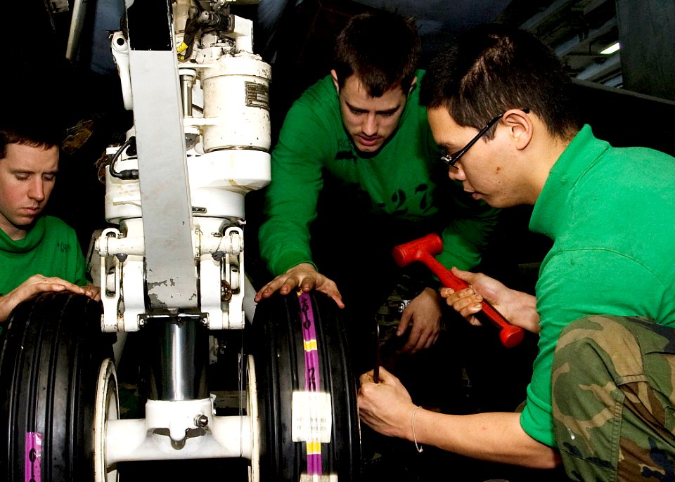 US Navy 101205-N-9626Y-106 Aviation Structural Mechanic 3rd Class Mark Tan, from San Diego, installs new landing gear on an F-A-18E Super Hornet ab