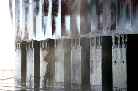 US Navy 101202-N-9643K-005 NASSCO shipyard workers use high-pressure water to clean the hull of the amphibious assault ship USS Bonhomme Richard (L