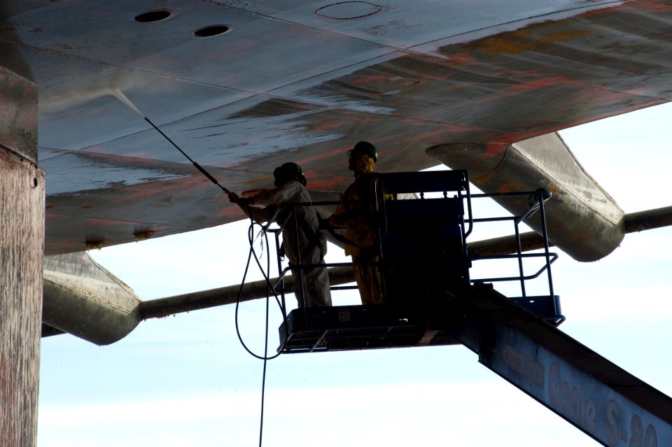 US Navy 101202-N-9643K-027 NASSCO shipyard workers use high-pressure water to clean the hull of the amphibious assault ship USS Bonhomme Richard (L