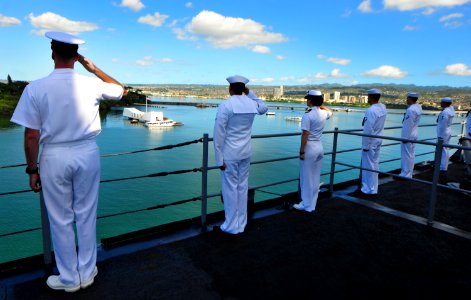 US Navy 101206-N-7948R-301 Sailors render honors as the amphibious dock landing ship USS Pearl Harbor (LSD 52) passes the USS Arizona Memorial duri