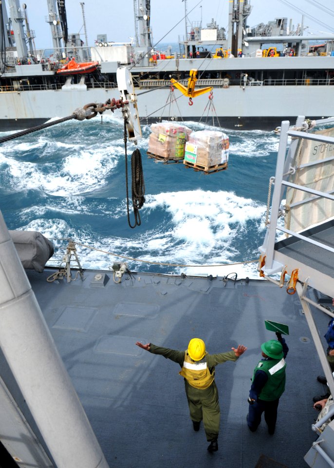 US Navy 101202-N-8721D-061 Sailors aboard USS Mustin (DDG 89) guide supplies from USNS Pecos (T-AO 197) during a replenishment at sea