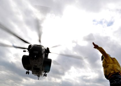 US Navy 101205-N-3620B-051 Aviation Boatswain's Mate (Fuel) Airman Adam Pond signals for an MH-53 Sea Stallion helicopter to take off from USS Denv