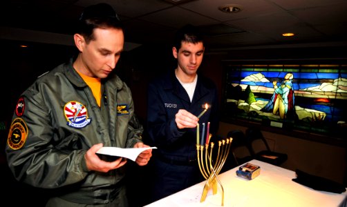 US Navy 101203-N-7103C-028 Yeoman Seaman Kevin Tucker, from Quaker Town, Penn., lights the Menorah during the third day of Hanukkah while Lt. Cmdr