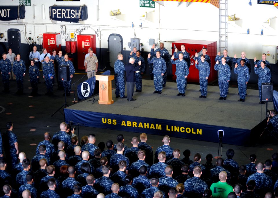 US Navy 101206-N-4973M-111 Secretary of Defense Robert M. Gates administers the oath of enlistment to 13 Sailors during an all-hands call aboard th