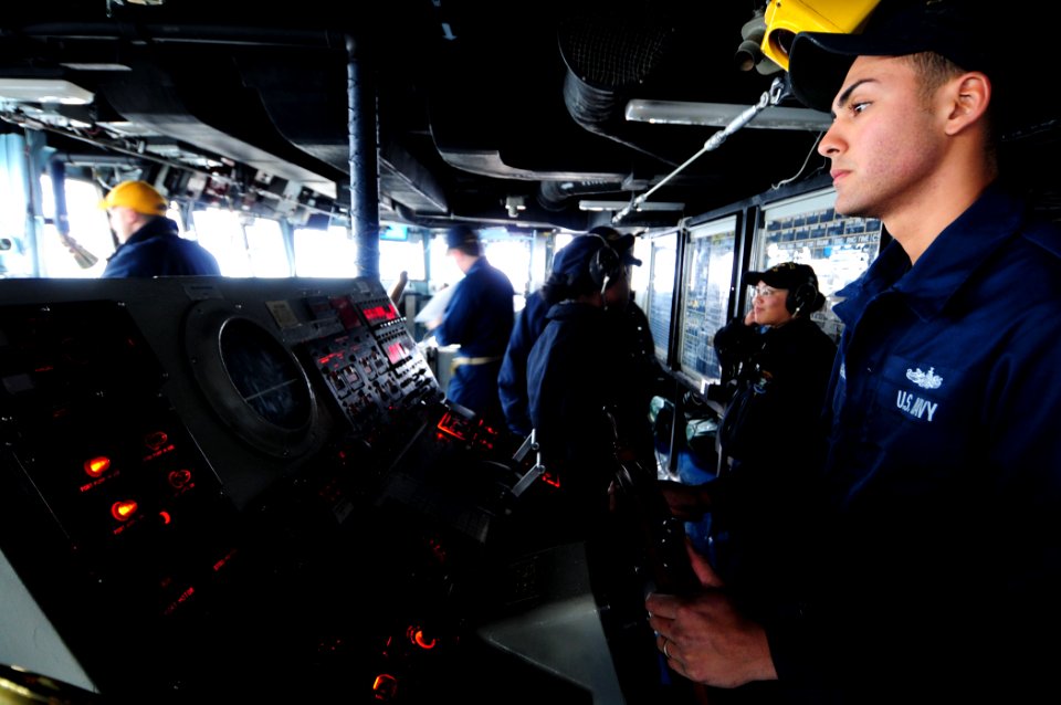 US Navy 101210-N-3659B-038 Boatswain's Mate Seaman Gustavo Benavides steers the ship while serving as helmsman aboard USS Comstock (LSD 45)