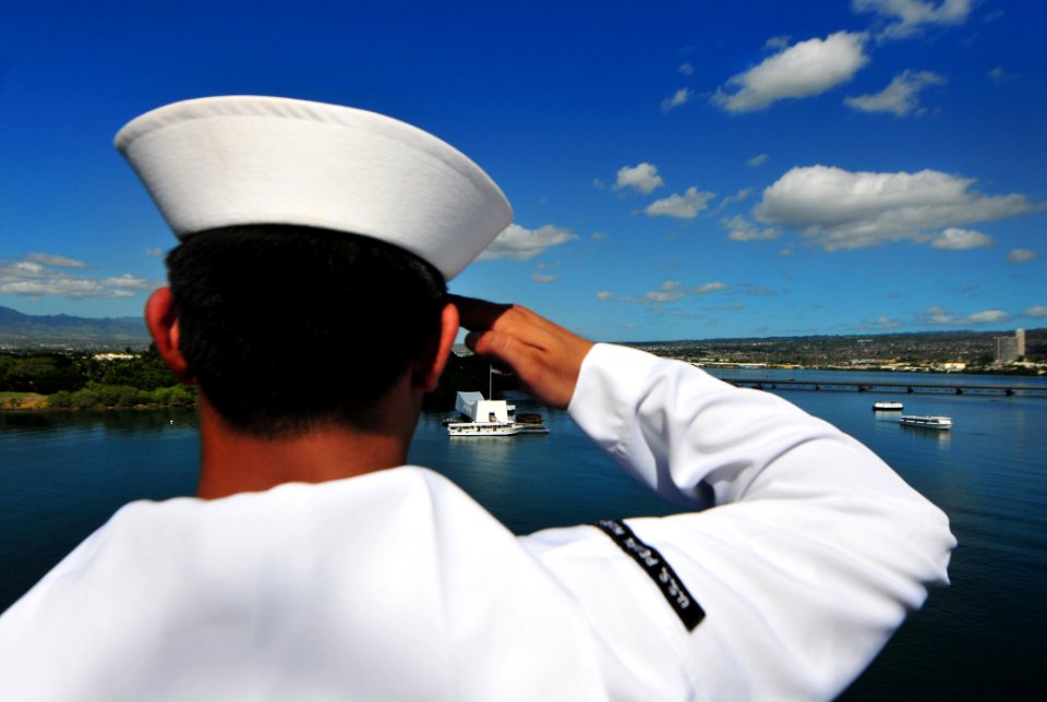 US Navy 101206-N-7948R-303 Information Systems Technician 2nd Class Eli Gonzalez renders honors as the amphibious dock landing ship USS Pearl Harbo