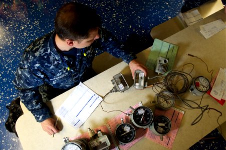 US Navy 101206-N-9643K-075 Aviation Electronics Technician 3rd Class David Ferguson checks the calibration of various types of gauges aboard the am