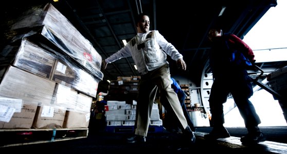 US Navy 101208-N-2055M-437 Chief Logistic Specialist Noe Nesmith guides a pallet of food to the hangar bay aboard the aircraft carrier USS Carl Vin