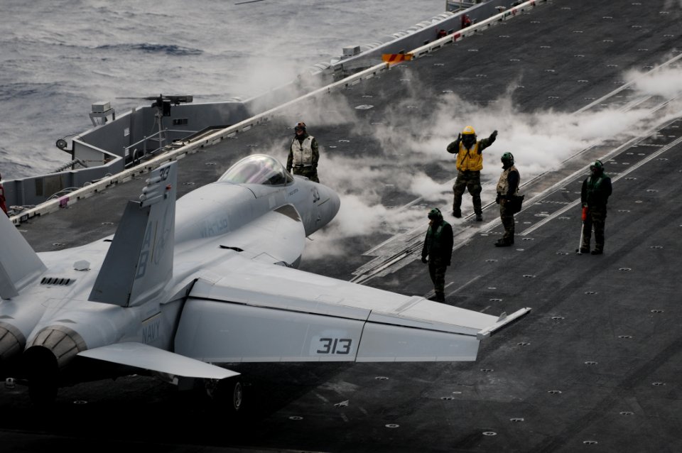 US Navy 101209-N-9693M-003 An Aviation Boatswain's Mate (Handling) directs an F-A-18E Super Hornet aboard USS Enterprise (CVN 65)
